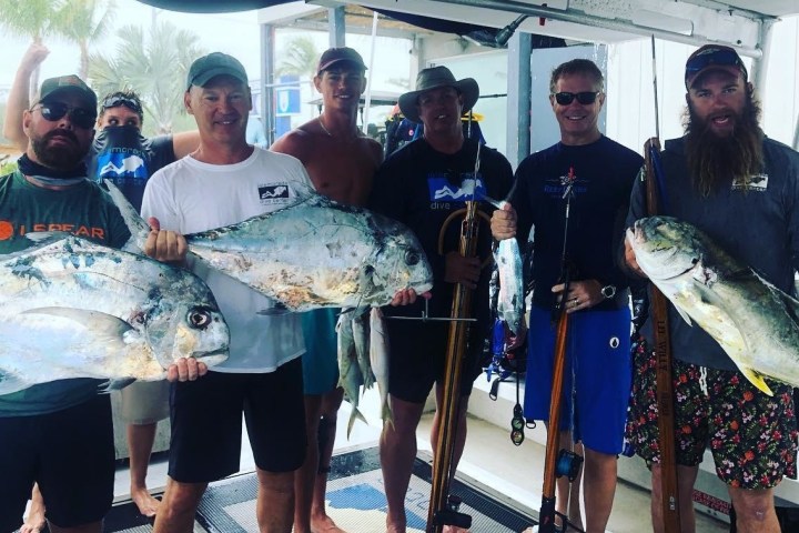 a group of people standing next to a person holding a fish